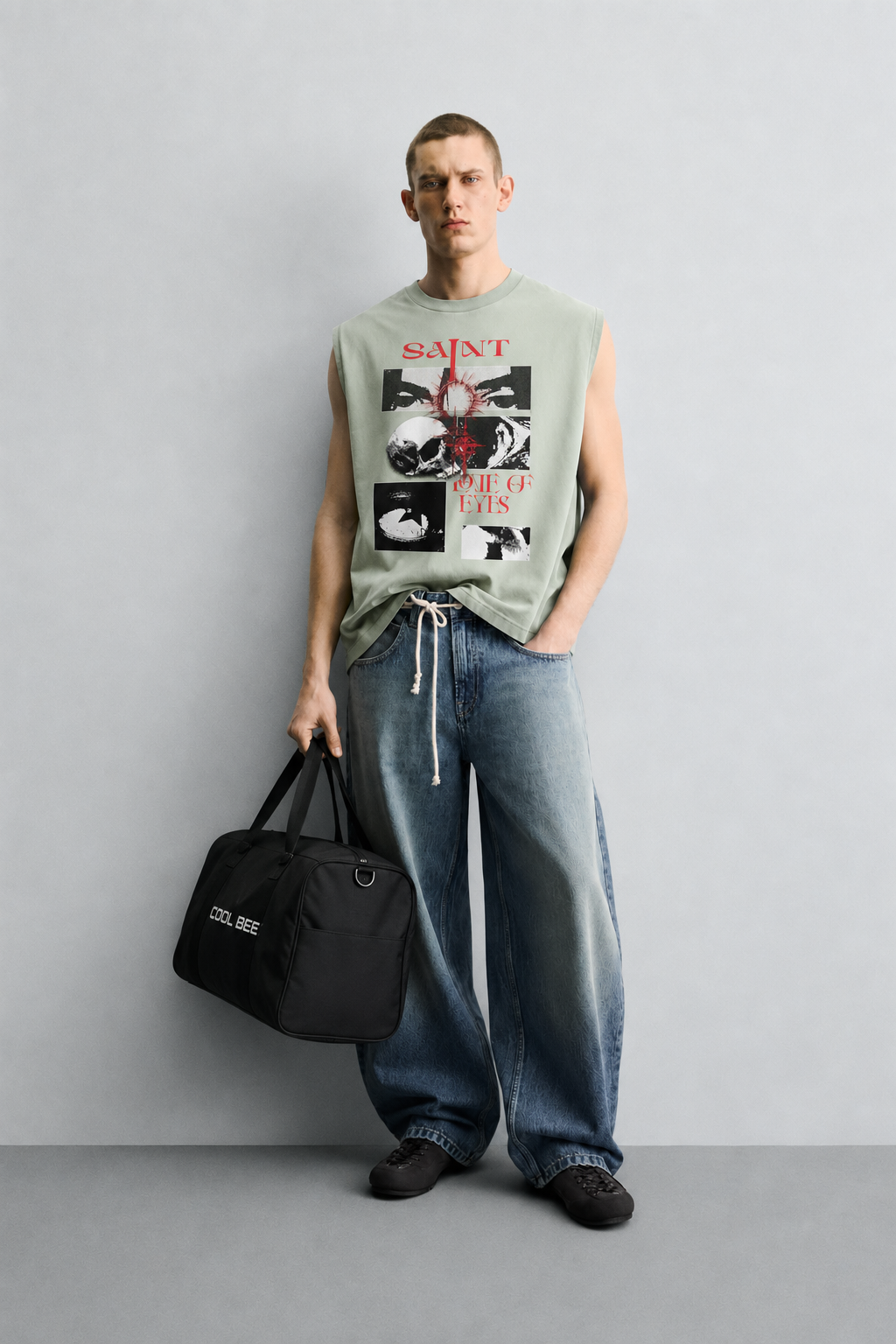Sage green tank top with red 'Saint' lettering above a black-and-white photo grid featuring a radiant eye, a skull, a close-up face, and an abstract textured panel.