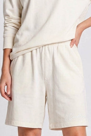 Person wearing a white outfit with shorts on a plain background