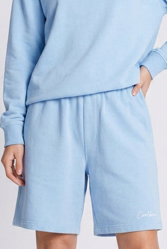 Person wearing a light blue sweatshirt and shorts set on a white background