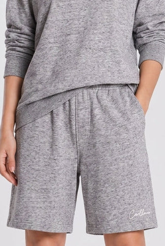 Person wearing a gray sweatshirt and shorts set on a white background